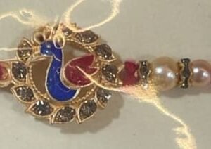 Enamel peacock with rhinestones, framed by pearls and beads Rakhi
