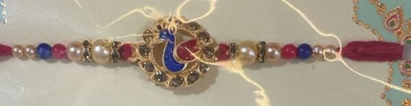 Enamel peacock with rhinestones, framed by pearls and beads Rakhi